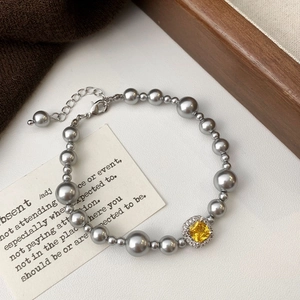 Détail du bracelet en perles grises avec zircon jaune carré et fermoir mousqueton robuste