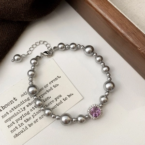 Détail d'un bracelet élégant en perles grises avec zircon rose carré et finition luxueuse