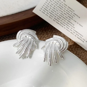 Macro shot of silver woven heart earrings showing intricate texture on white ceramic