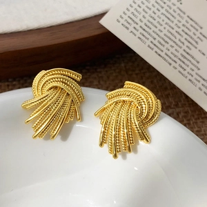 Detailed close-up of golden woven stud earrings with vintage twisted metal textures