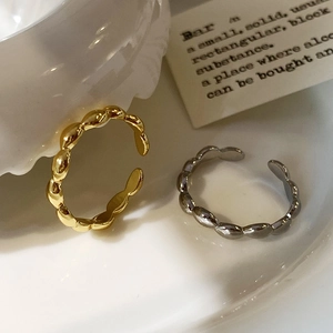 Macro shot of gold and silver twisted stackable open rings on a ceramic surface