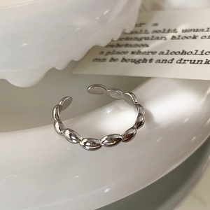Macro detail of silver adjustable ring with bead design on minimalist white ceramic