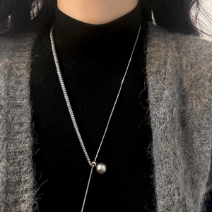 Elegant silver-toned pearl necklace with asymmetric chain design on a fashion model