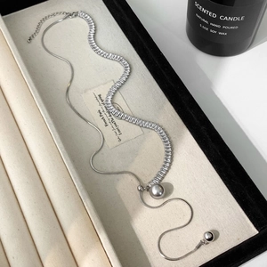 Detail of snake chain necklace with rectangular zircons and grey pearl drop pendant