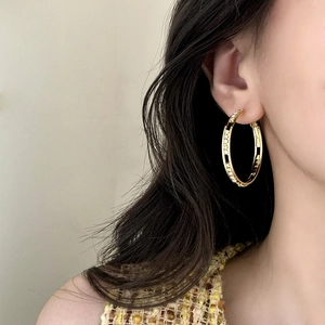 Élégantes créoles évidées dorées serties de zircons portées par un mannequin