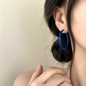 Close-up of deep blue resin hoop earring with polished finish worn by a model