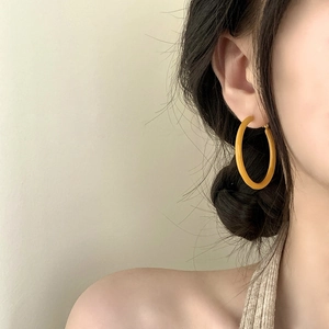 French vintage mustard yellow resin hoop earrings shown on a model in a minimalist style