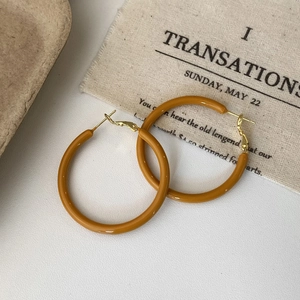 Macro shot of French vintage caramel orange enamel hoop earrings on aesthetic fabric