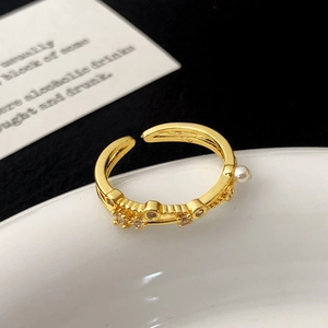 Close-up of a gold open ring featuring sparkling cubic zirconia and a lustrous white pearl