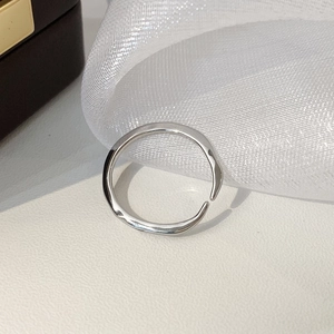 Vue macro d'une bague ajustable argentée au design liquide minimaliste et ondulé