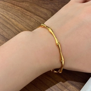 Golden geometric bamboo joint bangle in a minimalist open adjustable design on wrist