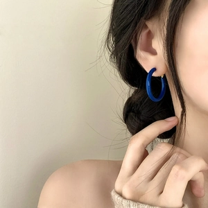 Nahaufnahme eines Models mit minimalistischen glänzend blauen Creolen für den Alltag