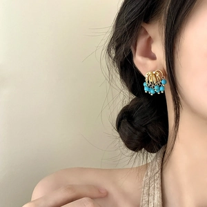Elegant gold cage earrings with turquoise beads on a model, luxury vintage style