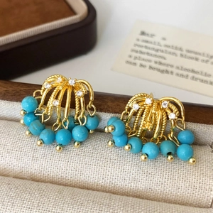 Detail of gold tassel earrings with zircon studs and sky blue turquoise beads