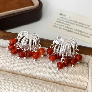 Macro detail of silver tassel earrings with red agate beads and sparkling zircon stones