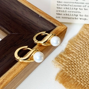 Detail of gold huggie earrings with white pearls on a rustic linen background