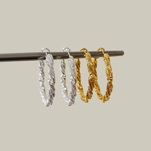 Modern twisted hoop earrings in gold and silver finish with detailed metallic texture