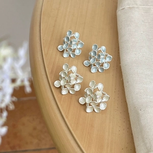 French vintage floral stud earrings in light blue and cream white on a wooden table