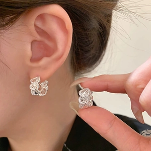 Elegant silver clover earrings with hollow floral design worn by a female model