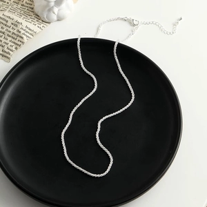 Macro detail of silver sparkling link chain with lobster clasp on elegant black tray