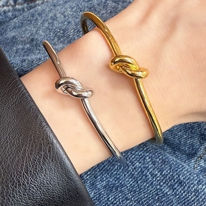 Minimalist polished knot bracelet in gold and silver finish shown on a wrist