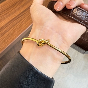 Macro view of minimalist gold knot bangle with a polished mirror finish on the wrist