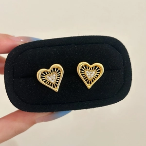 Elegant gold hollow heart earrings with white crystals in a black jewelry box