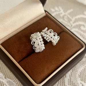 Detail of silver crown earrings with pearls on brown velvet jewelry box and lace