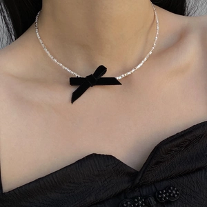 Silver beaded choker necklace featuring a black velvet bow on a model wearing black clothing