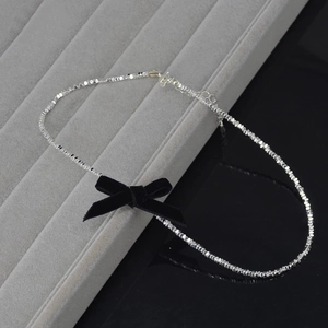 Detail of silver beaded choker necklace with a black velvet bow on a jewelry display