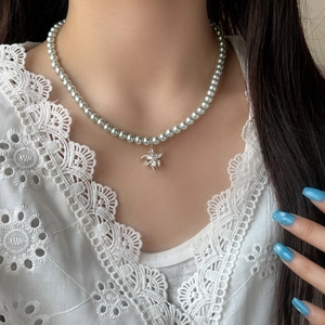 Collier élégant avec pendentif lys argenté et perles grises porté sur le cou d'une femme