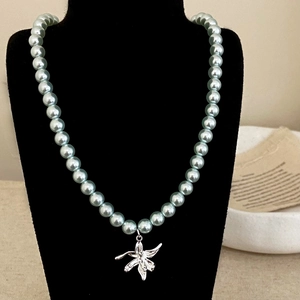 Vue détaillée d'un collier de perles bleu clair avec pendentif fleur de lys en argent