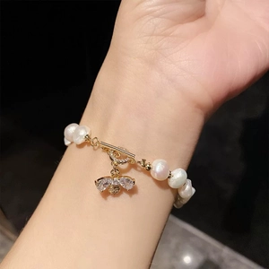 Bracelet perles baroques avec pendentif abeille et fermoir OT au poignet d'un mannequin