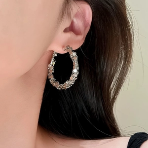 Silver textured hoop earring with multifaceted surface design shown on a model