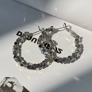 Macro shot of silver geometric faceted hoop earrings with shimmering light reflection
