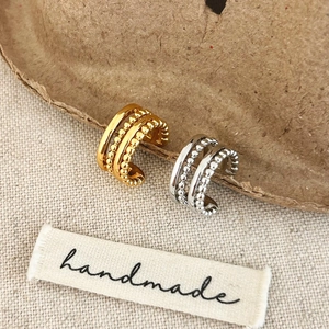 Handmade multilayer beaded ear cuffs in gold and silver finish on neutral fabric