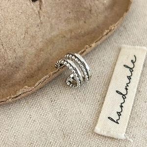 Detail of minimalist silver multi-layer ear cuff featuring polished bands and beaded chains