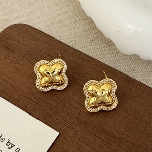 Detailed close-up of clover studs featuring quilted gold texture and zircon pavé edges