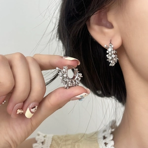 Elegant silver cluster earrings with pearls and crystals shown on model and held in hand