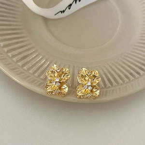 Detailed macro view of gold flower earrings with pavé set cubic zirconia centers