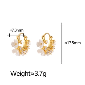 Close-up of gold hoop earrings with white flowers and sparkling crystals detail