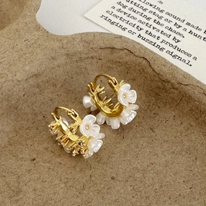 French vintage gold hoop earrings with white flowers and pearls on a textured background