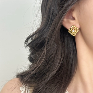 Elegant gold hollow flower stud earrings with center zircon on female model's ear