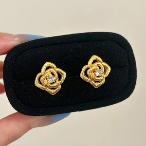 Detail of gold rose earrings with sparkling zircon center in a black velvet box