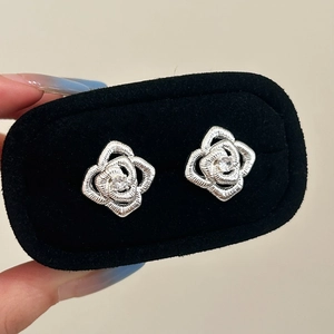 Detailed macro shot of vintage silver rose earrings with a central clear zircon stone
