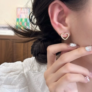 Elegant gold heart stud earrings with cubic zirconia worn by model in soft home light