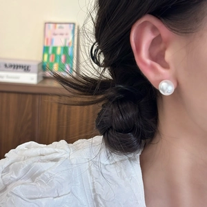 Detail of 12mm large white round pearl earring worn on model for an elegant look