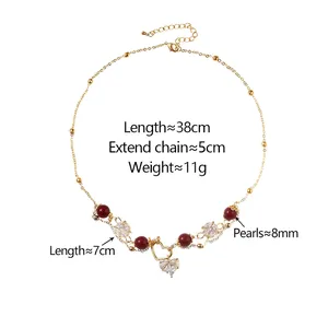 Collier élégant en perles dorées avec perles rouges et pendentifs cœur en zircon sur blanc
