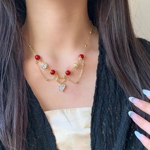 Collier double couche doré avec perles rouges et pendentif cœur en zircon sur mannequin
