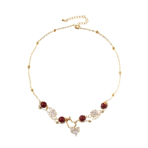 Collier doré élégant avec perles bordeaux et pendentif cœur en cristal sur fond blanc